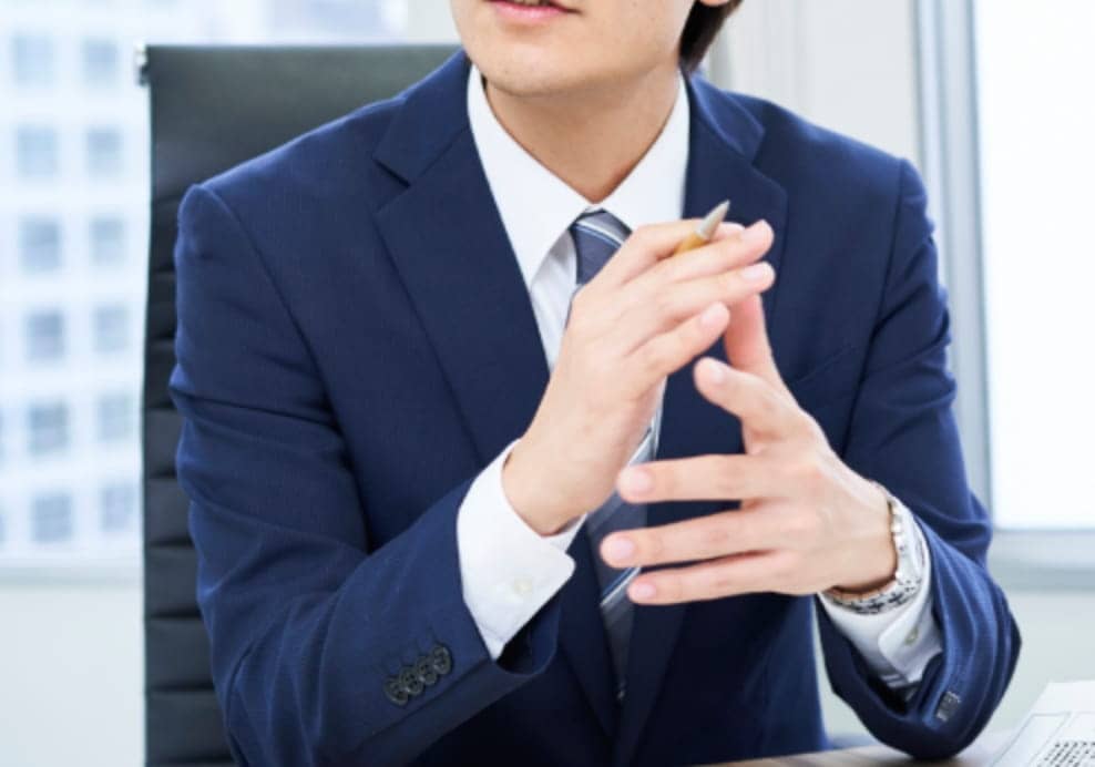 スーツ姿の男性が手振りで説明している様子